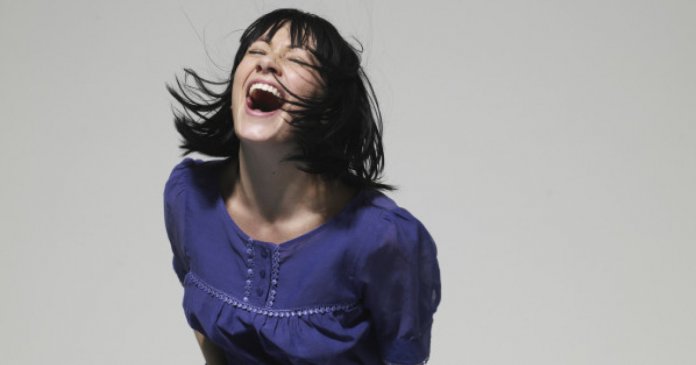 Young woman laughing, eyes closed