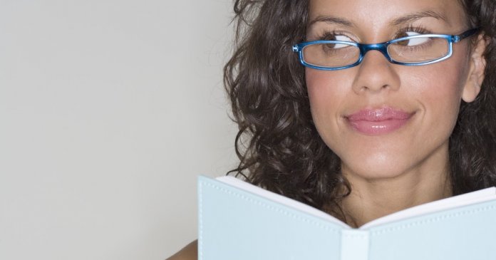 Young Woman Looking Away from Book --- Image by © Royalty-Free/Corbis