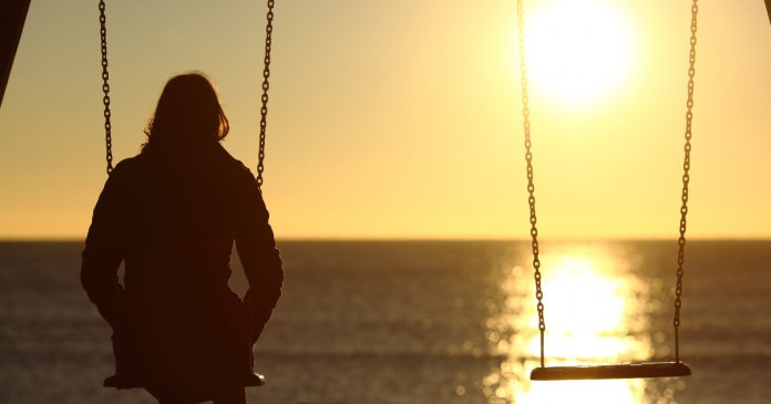 Lonely woman watching sunset alone in winter