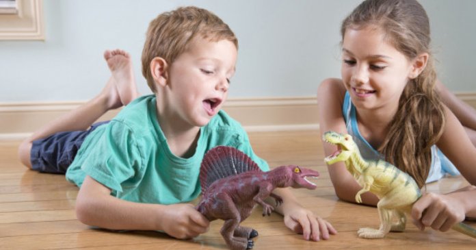 Young girl and boy playing with toy dinosaurs.