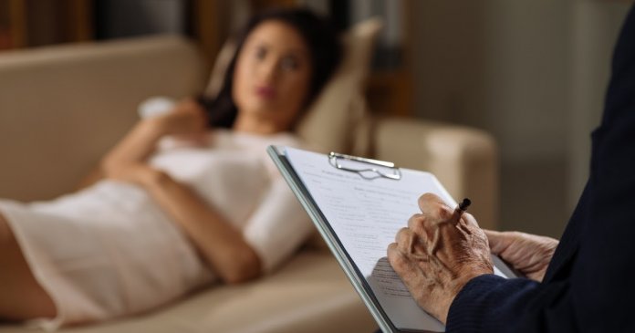 Mature psychiatrist making notes during the session with female client