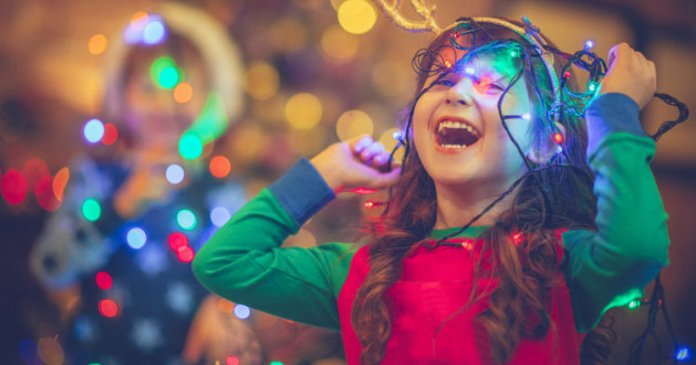 Little girl and boy in Christmas playing with lights