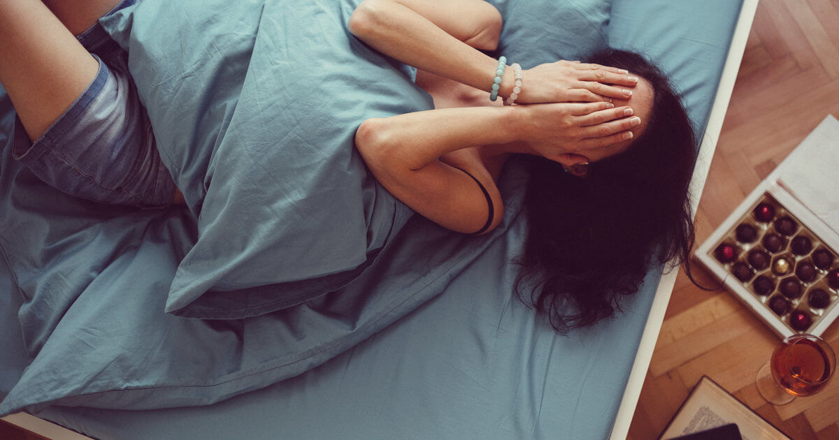Depressed woman in bed with hands on face