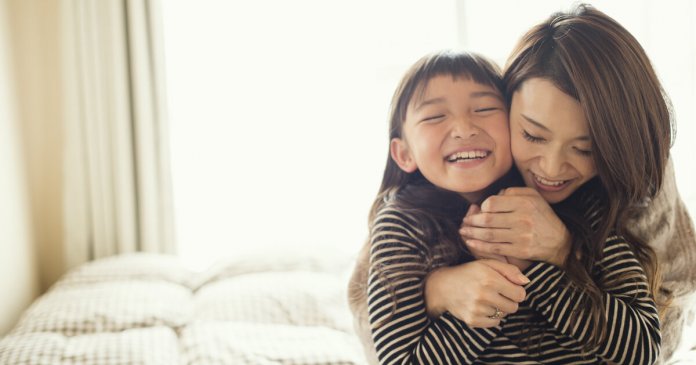 Mother and daughter having fun time in bed room