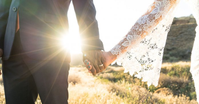 Interracial couple holding hands at wedding