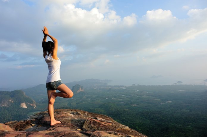 woman mountain peak cliff practice yoga