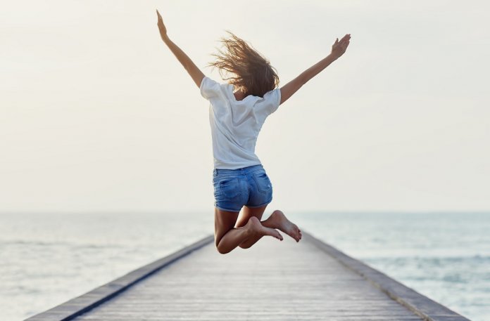 Back view of jumping girl on the pier