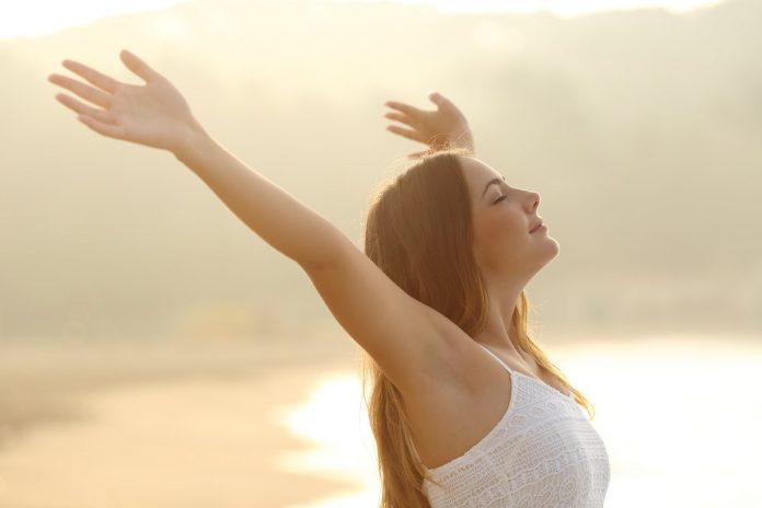 Relaxed Woman Breathing Fresh Air Raising Arms At Sunrise