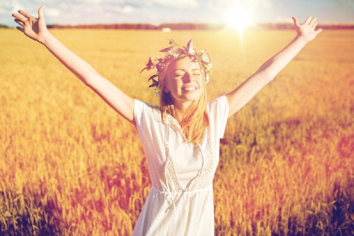 happy young woman in flower wreath on cereal field